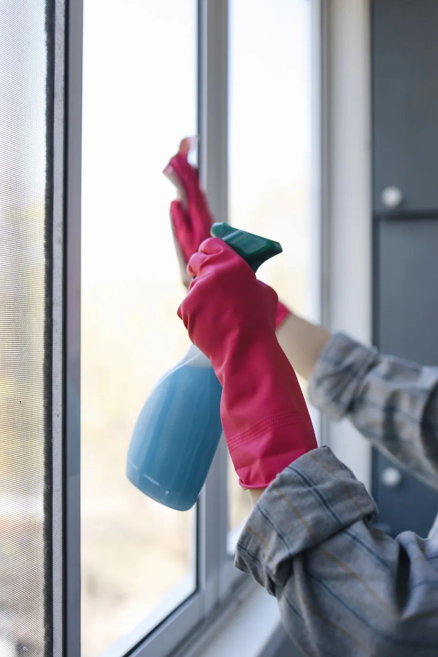 Fensterreinigung mit Handschuhen und Reinigungsmittel